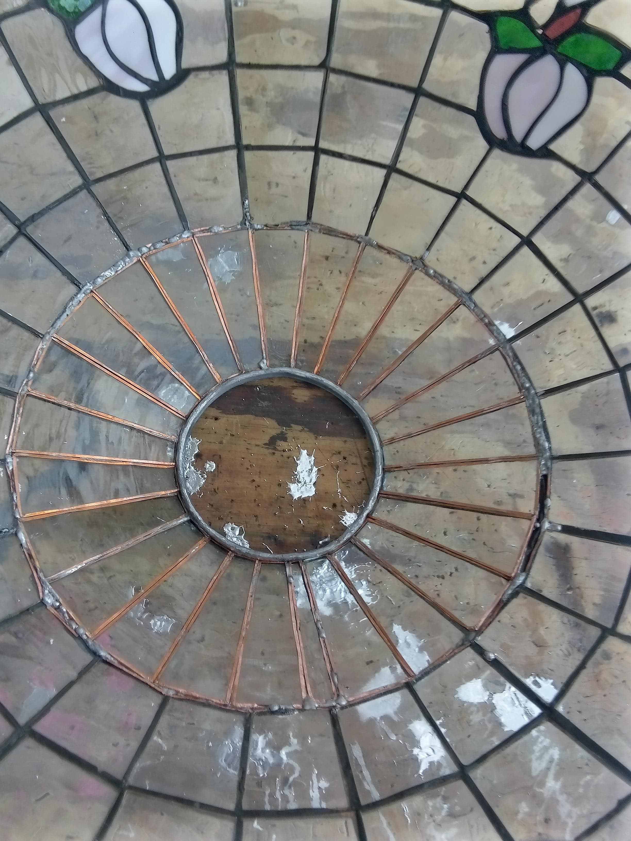 Interior view of a stained glass lampshade with radiating copper lines and geometric glass panels.